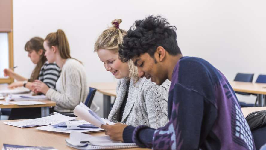 Students studying at a table, reading papers