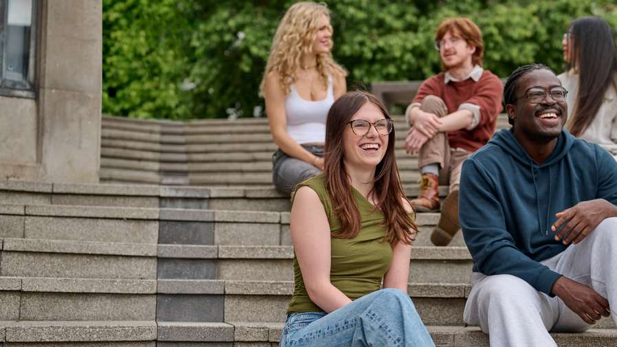 Smiling students sitting on steps .