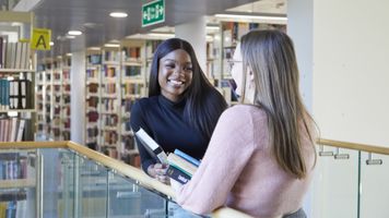 alt="Students talking in the UEA Library"