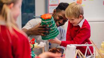Young teacher is helping one of his primary school students during arts and crafts lesson.