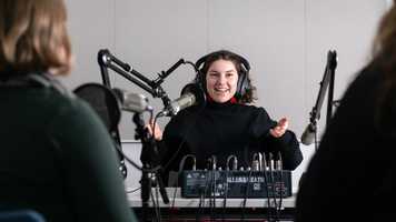 A student wearing headphones speaking into a microphone in a studio setup
