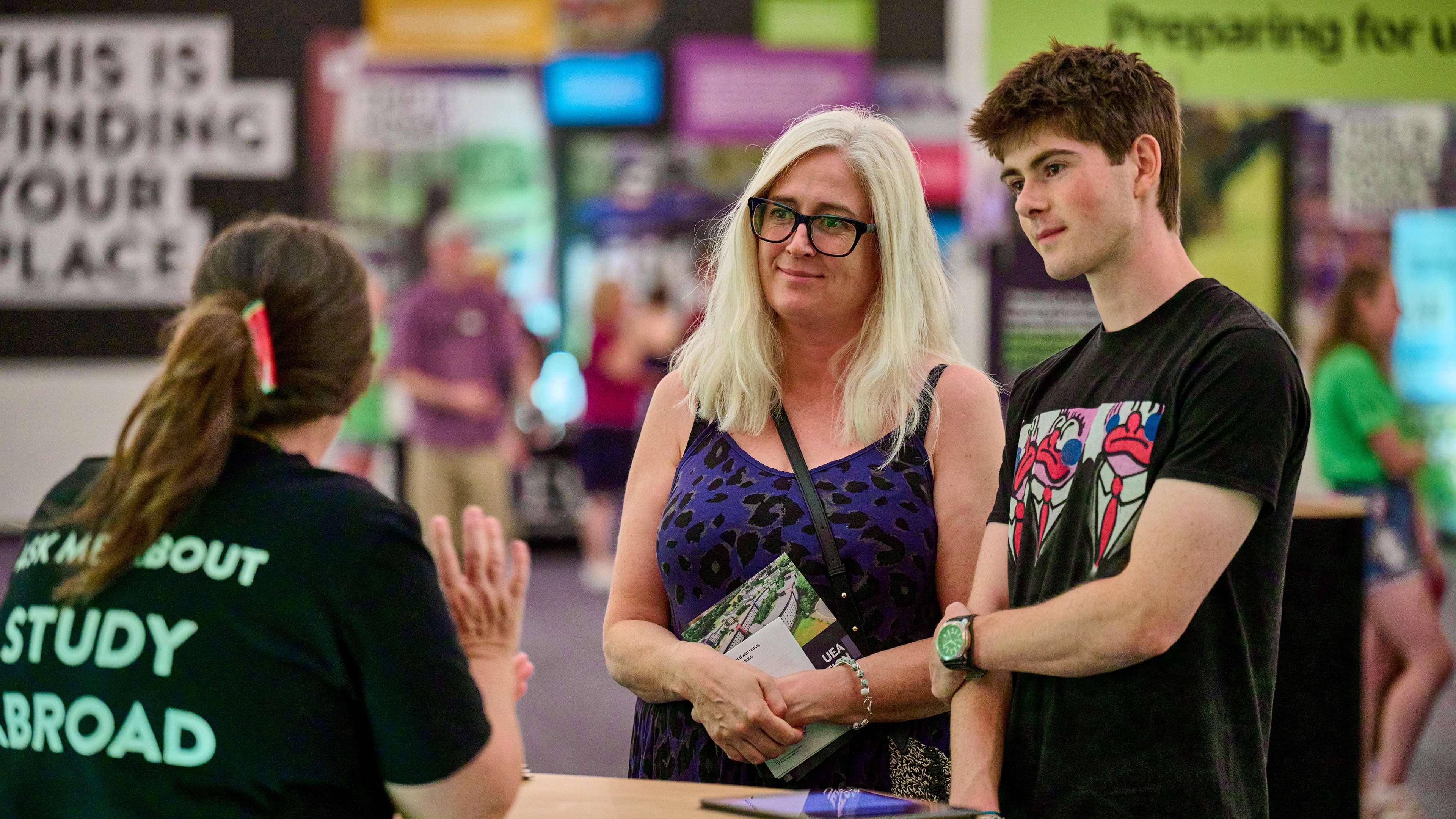 Two people speak to somebody in the information zone at an open day.