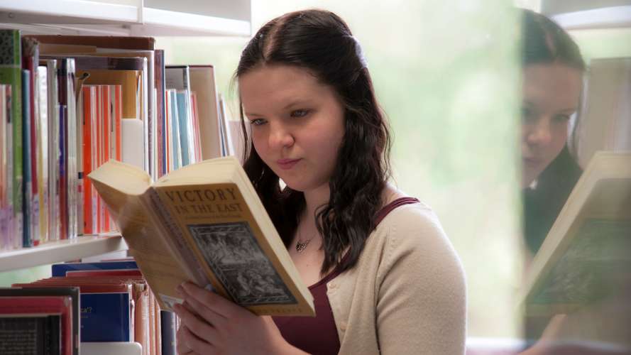 A UEA student is pictured reading a book in the library building on the UEA campus