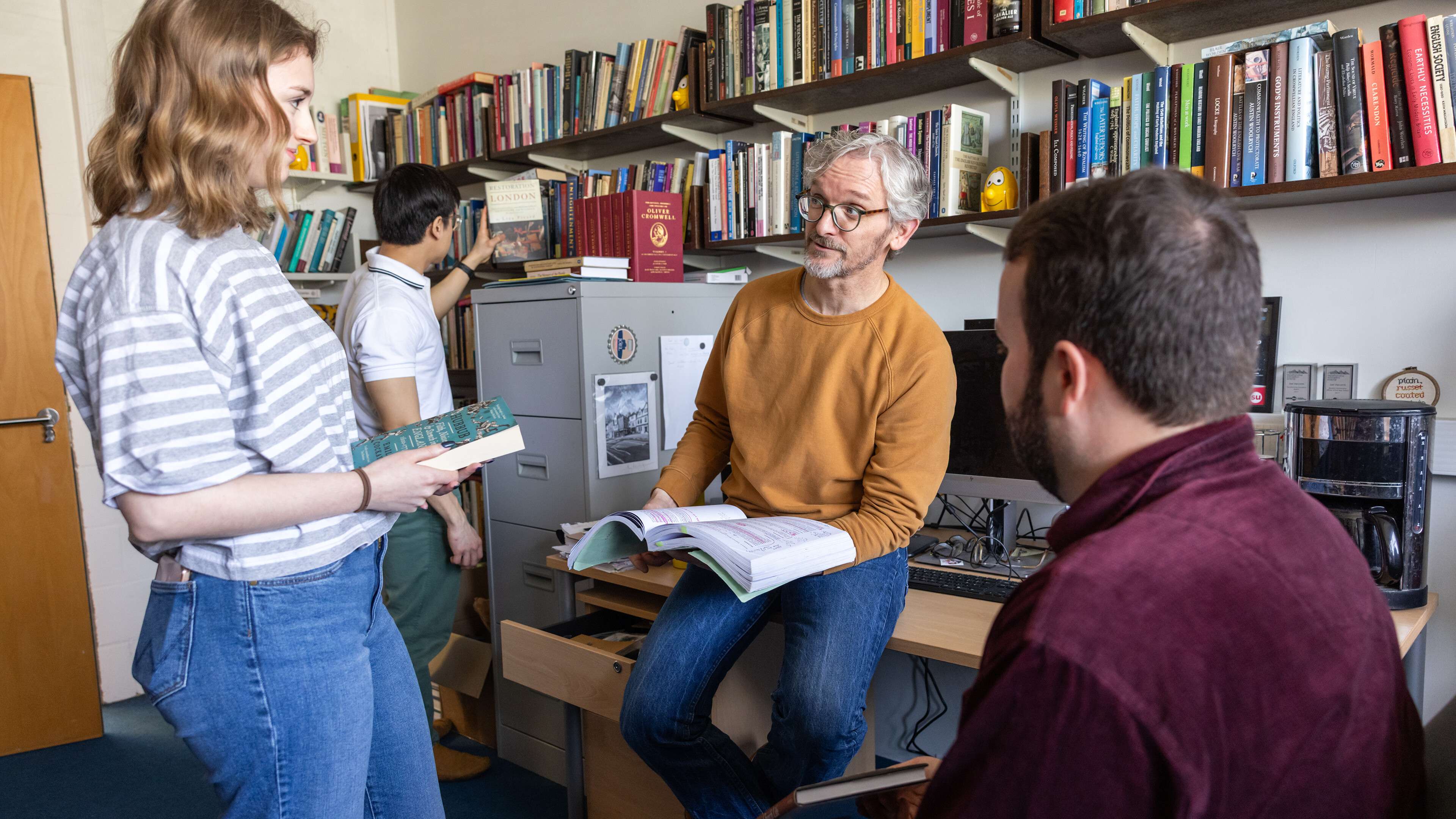 History students and a lecturer browsing books in an academic office