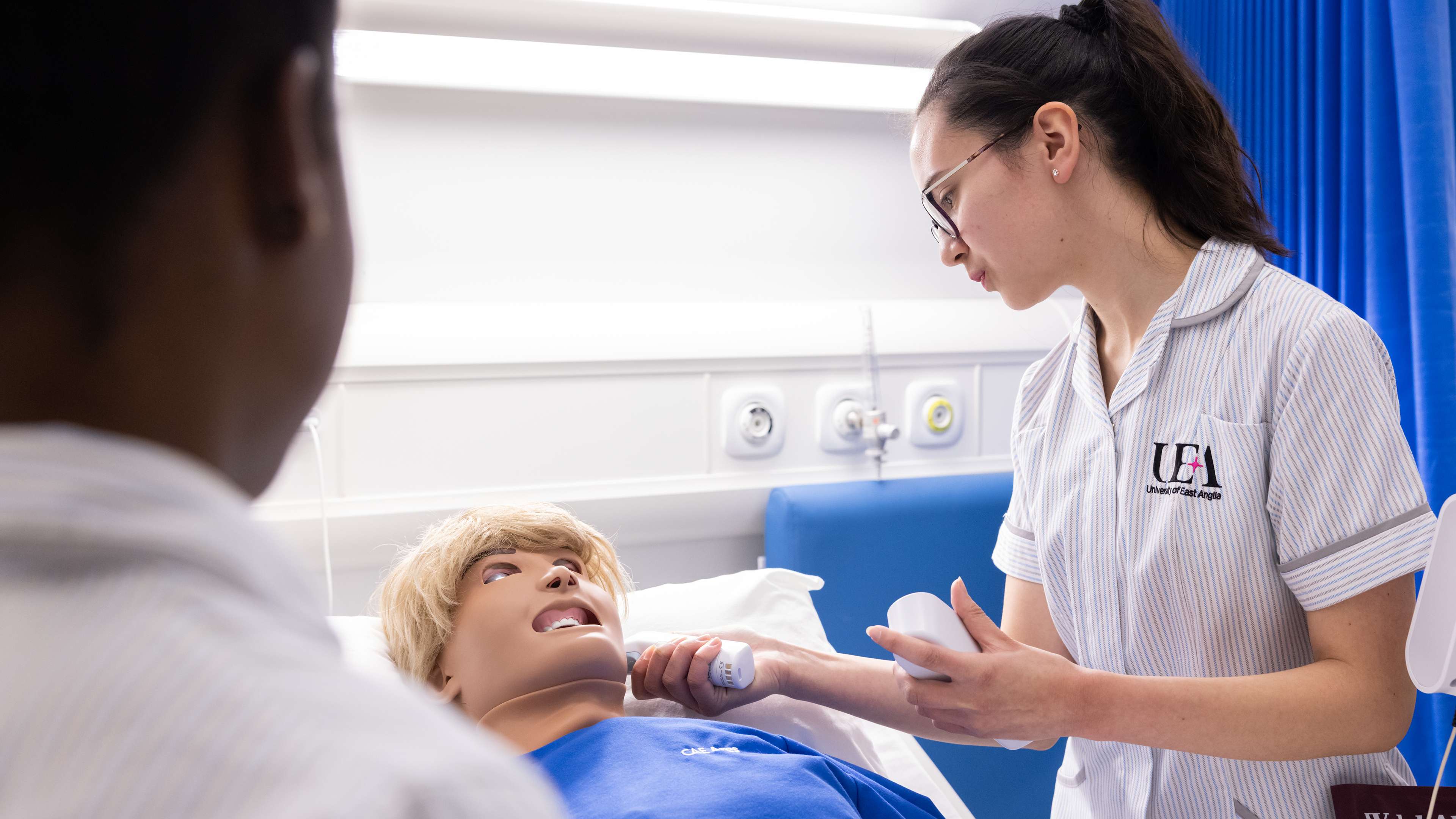 Nursing students over a dummy performing medical examinations