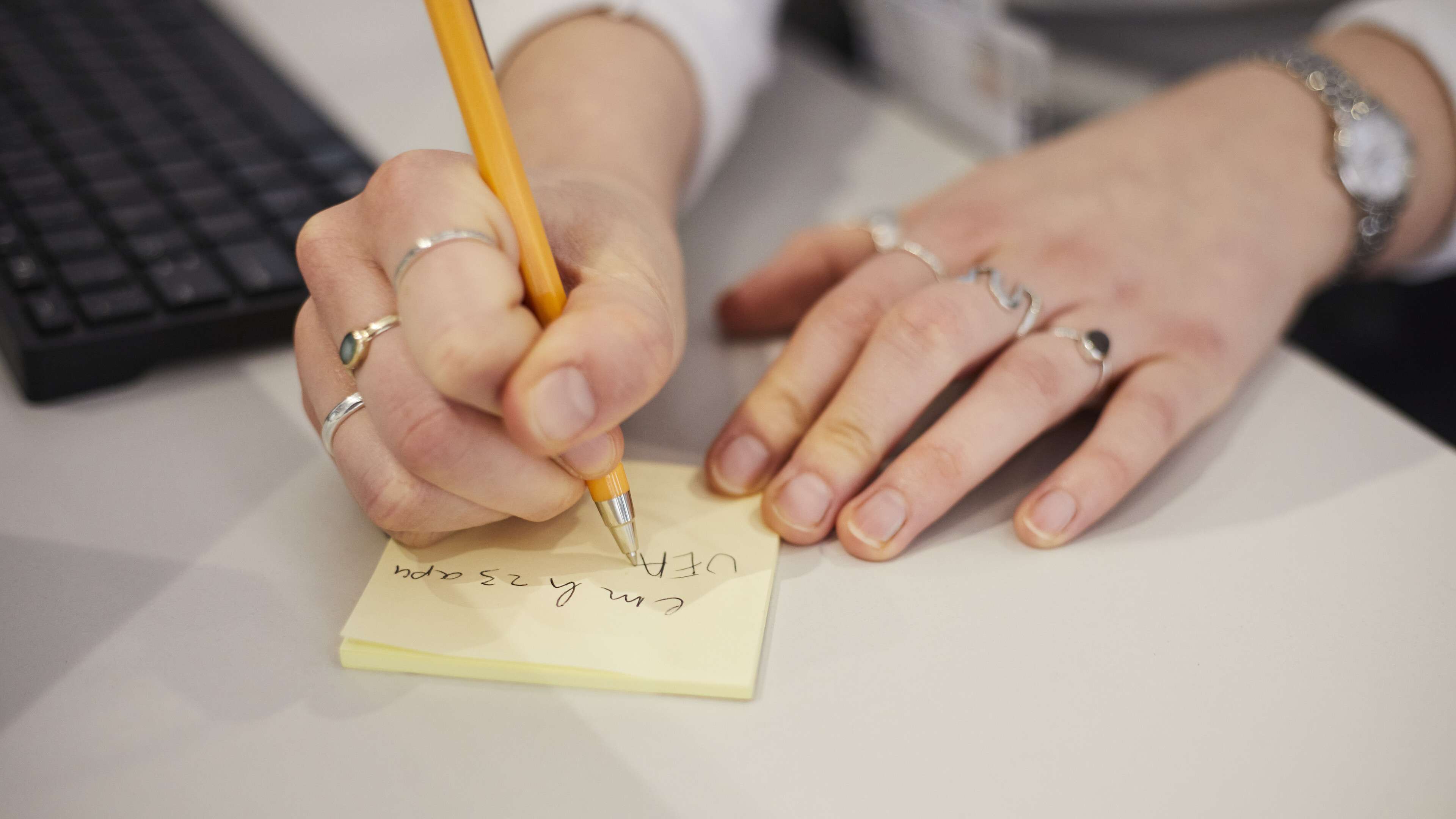 Person writing on Post-it note