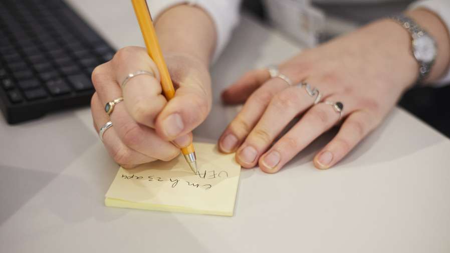 Person writing on Post-it note
