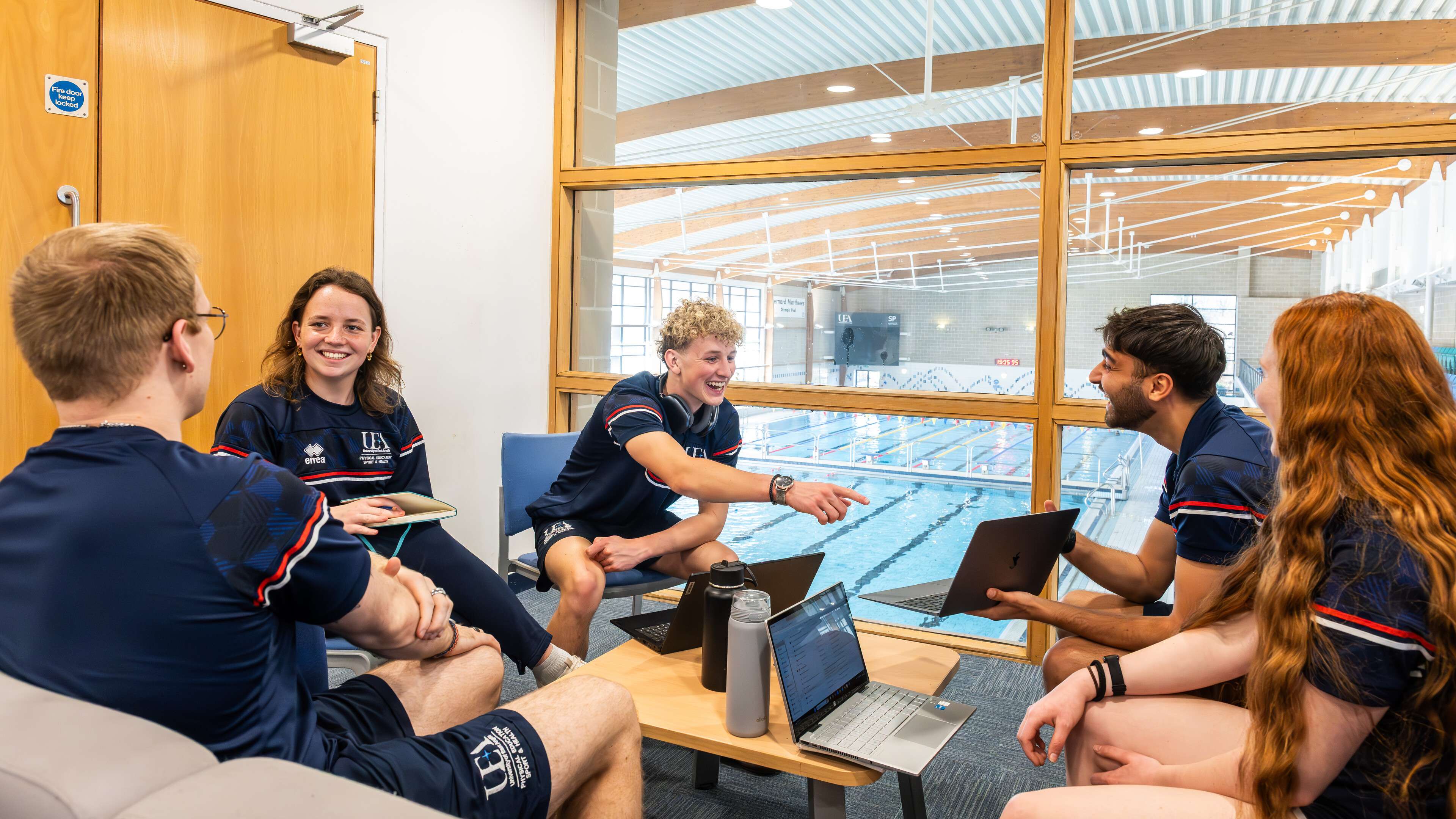 A group of students in the Sportspark with the swimming pool in the backrgound