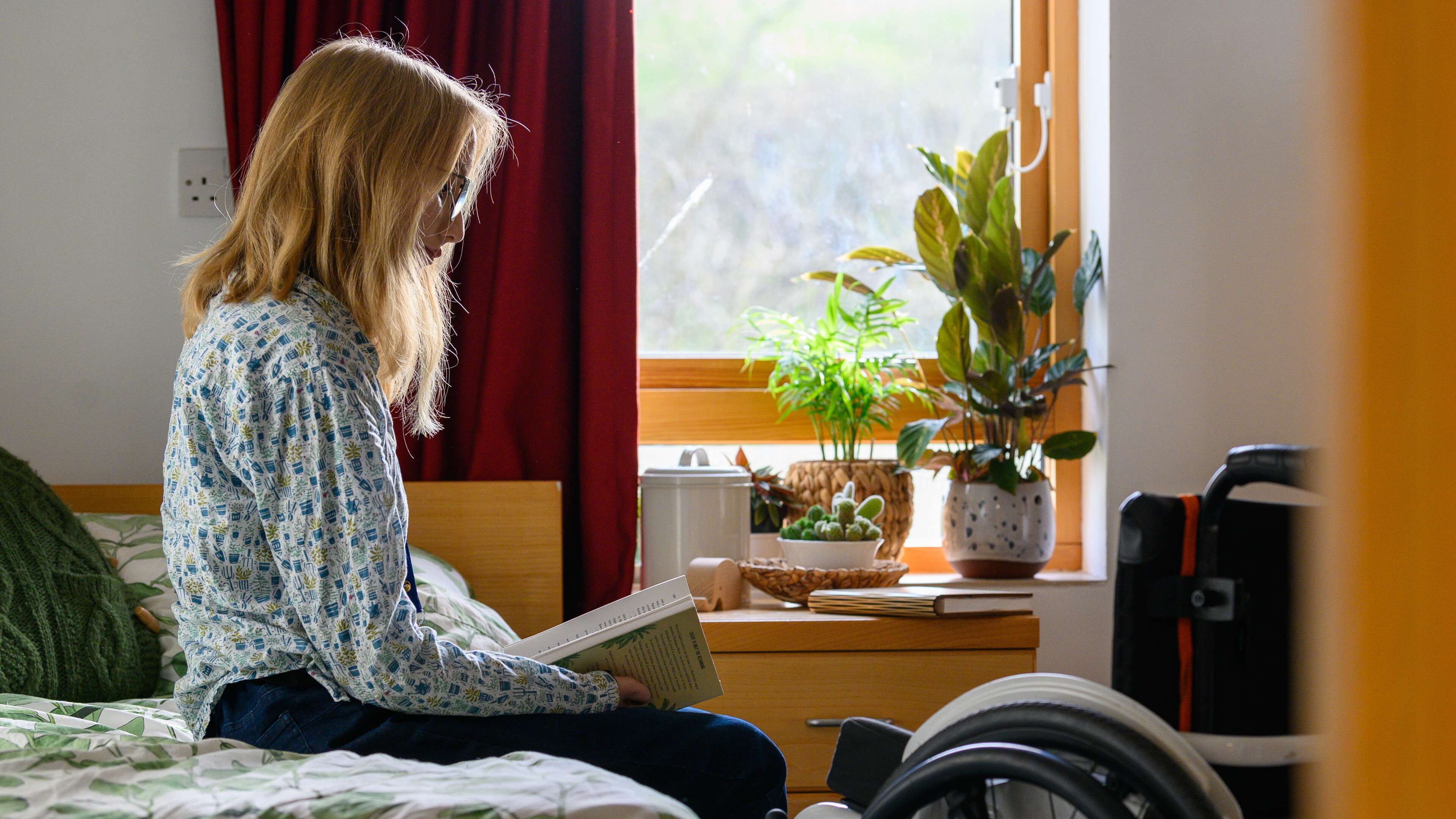 A UEA student reading a book in a room specially adapted for wheelchair users