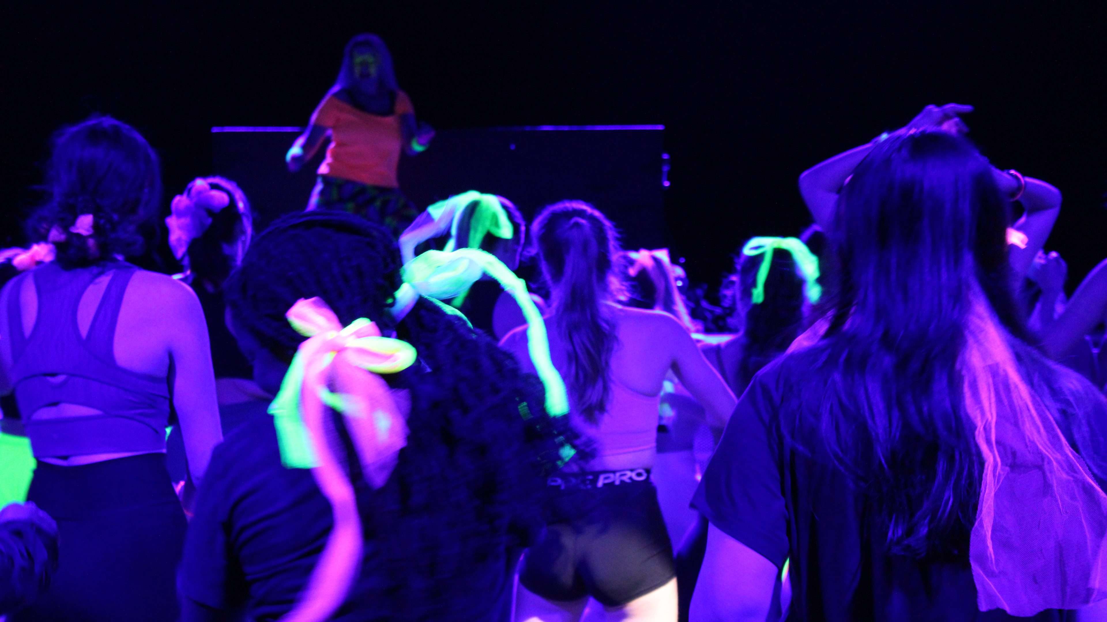 A group of people wearing glow in the dark clothing taking part in a zumba class.