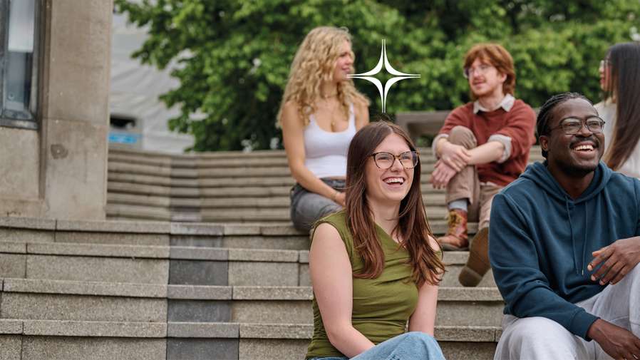 A group of students laughs on steps at the UEA