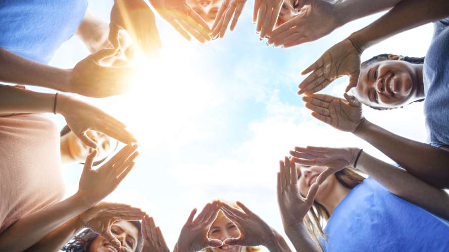 Various people showing their hands with the sky in the background
