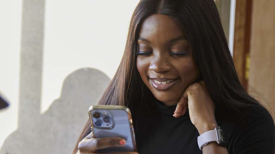 student smiling at phone in library