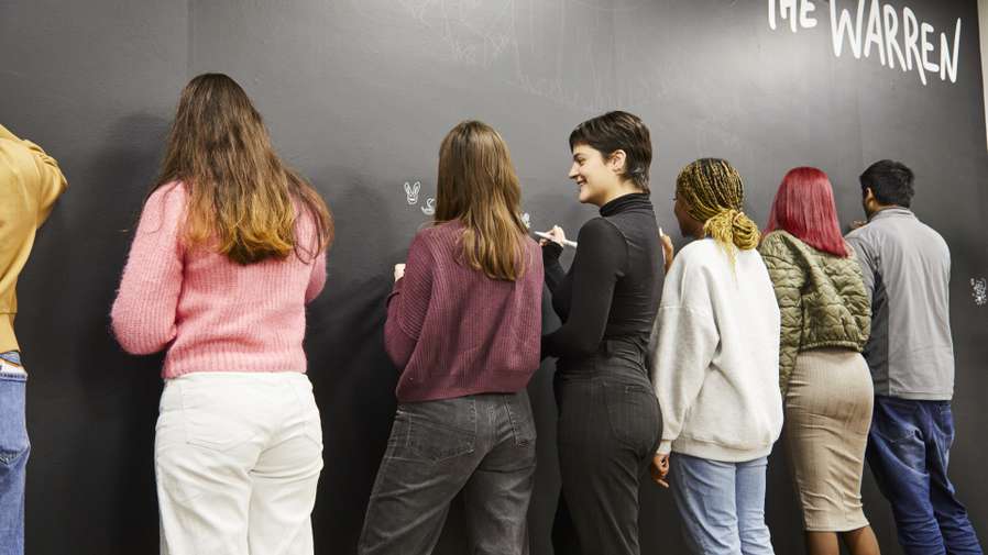 Students drawing on the board in The Warren
