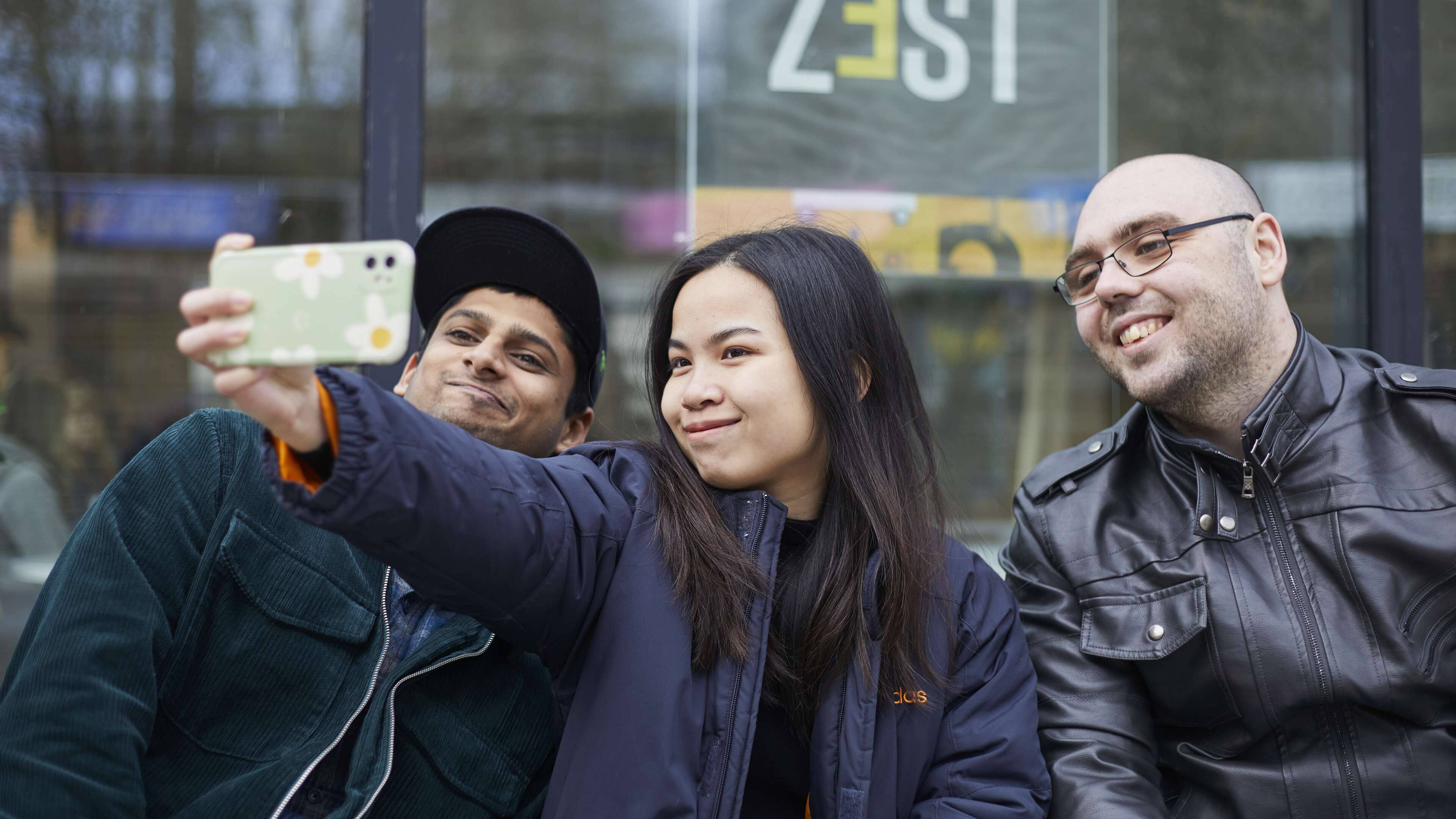Girl in middle holding hone taking a selfie with two others