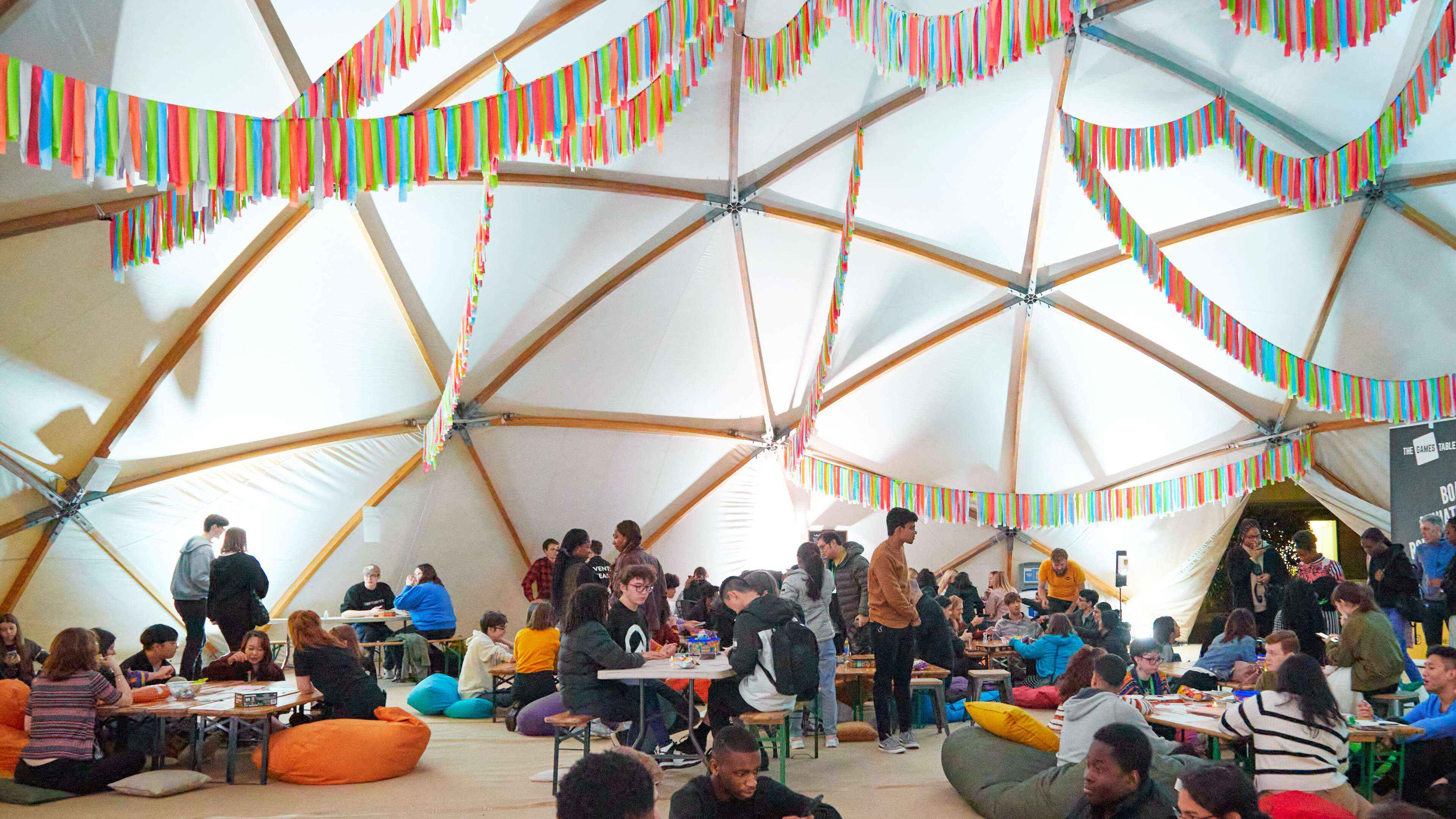 Groups of students playing games and socialising in a large colourful tent.