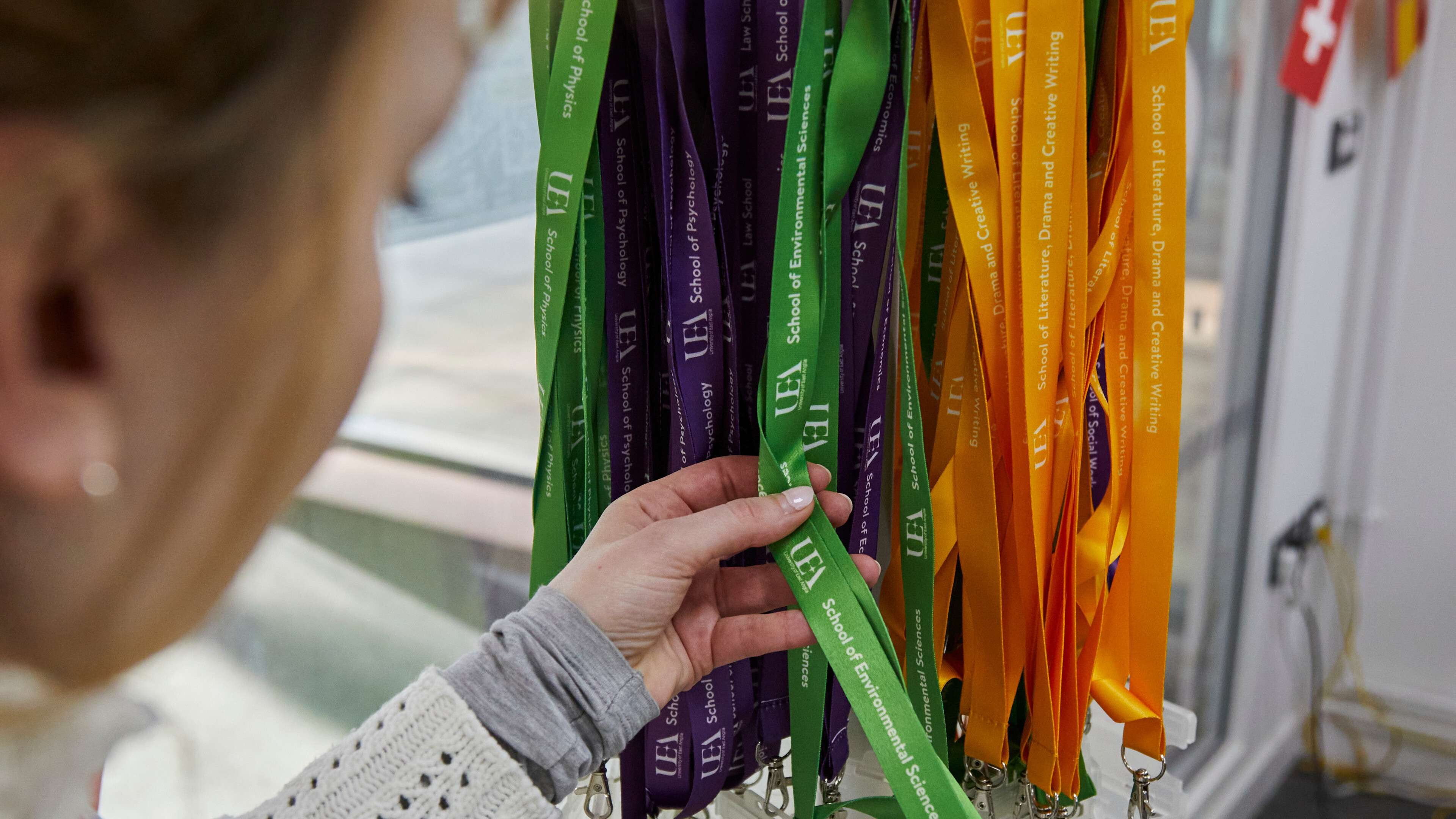A person looking through a number of brightly coloured lanyards.