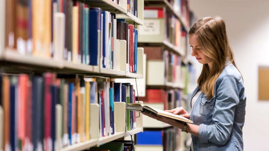 Student reading a book in the Library on campus