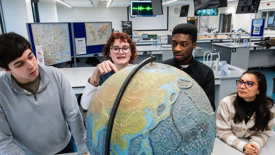 Environmental science and geography students looking at a globe in a laboratory.