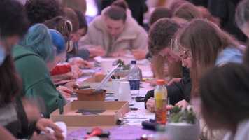 Students sitting at a long table and taking part in crafting activities.