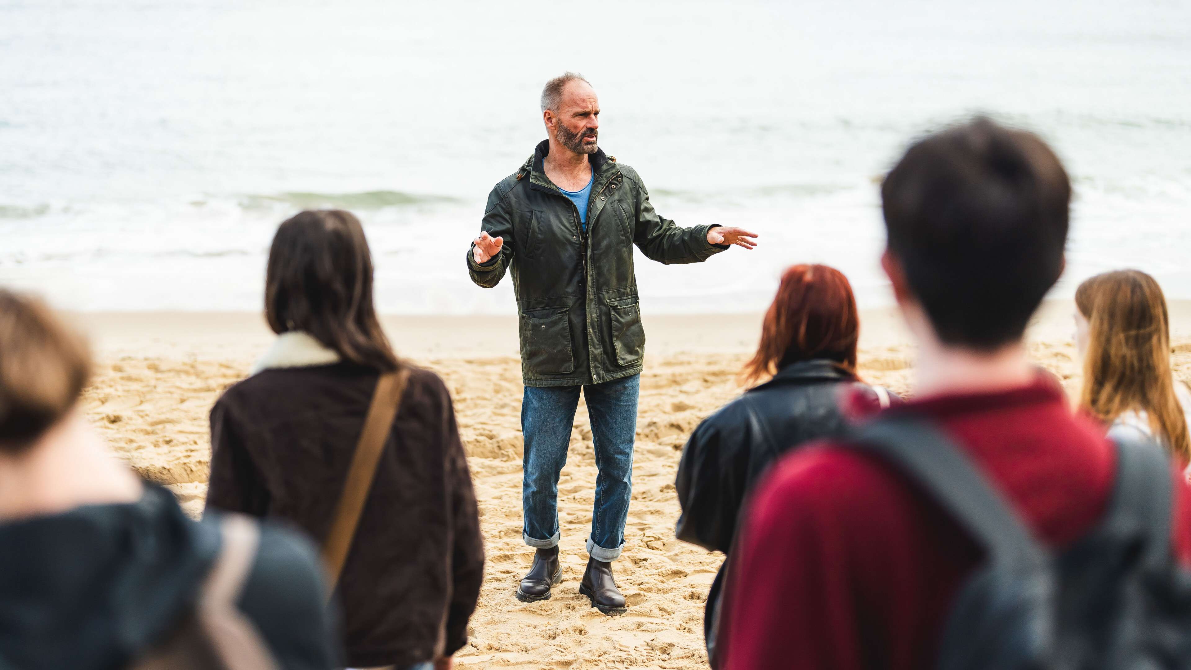 Environmental science lecturer teaching students on the beach at Sea Palling