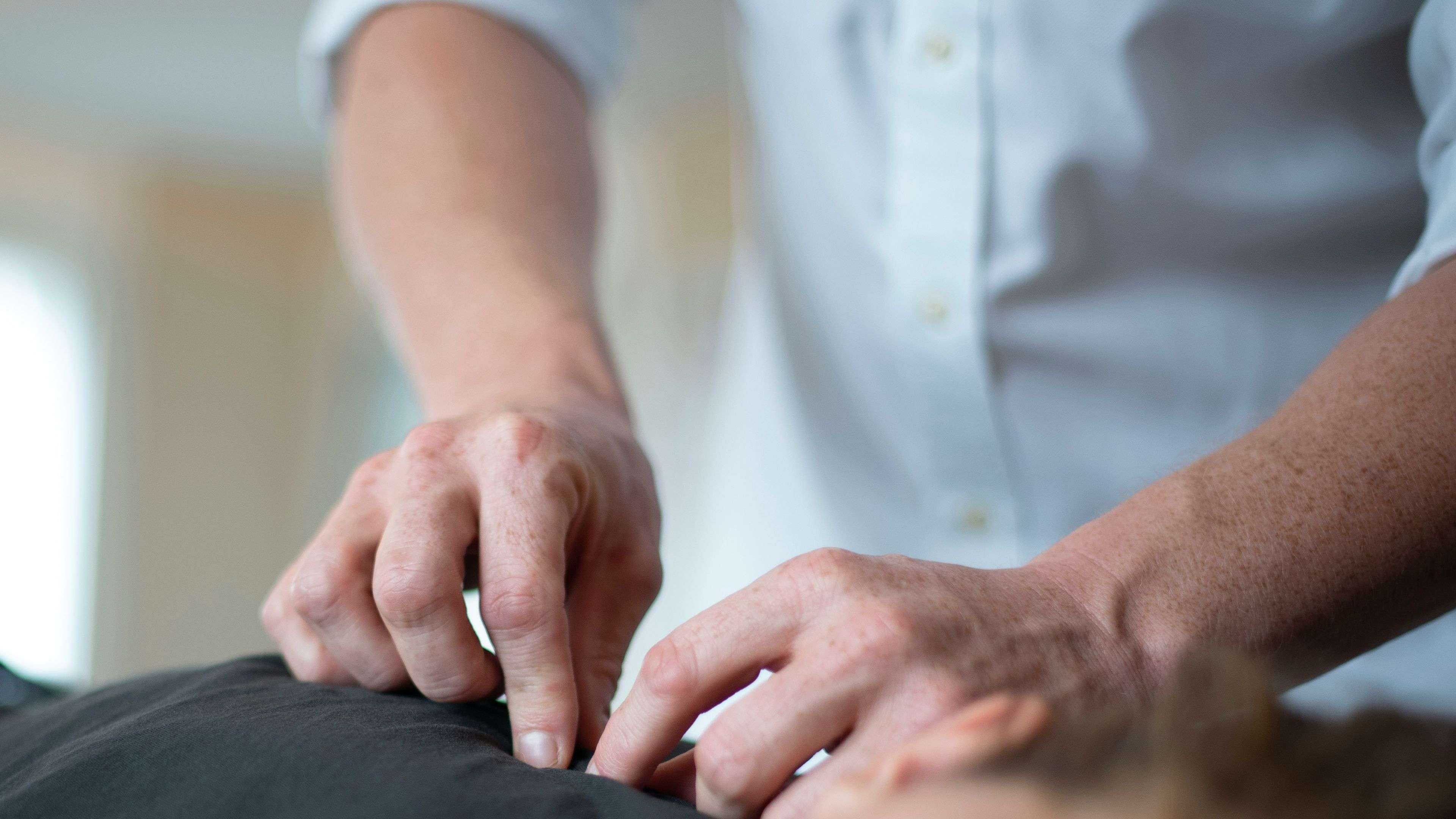 Hands performing a massage on a person's back.