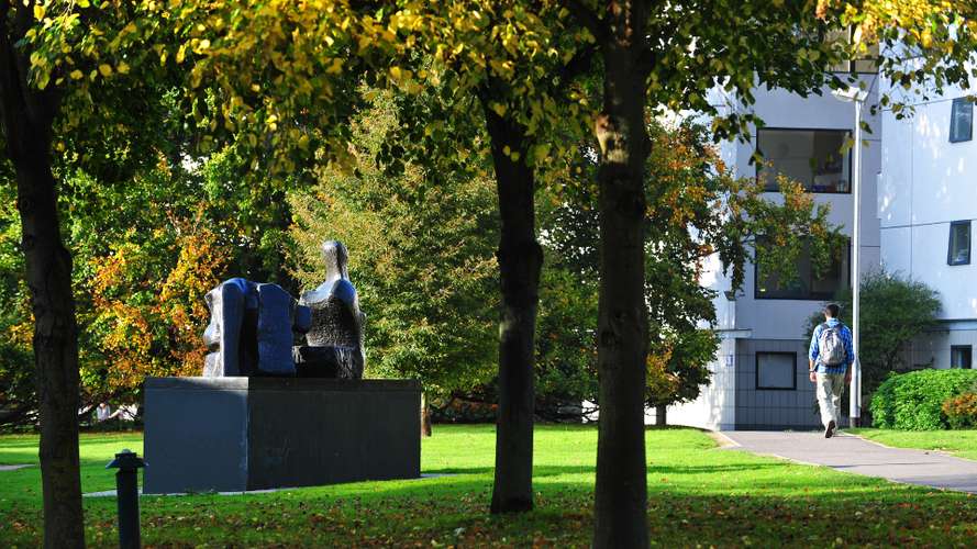 Student walking on Campus by the Henry Moore Statue
