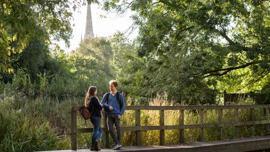 Students on river walk in view of Norwich cathedral