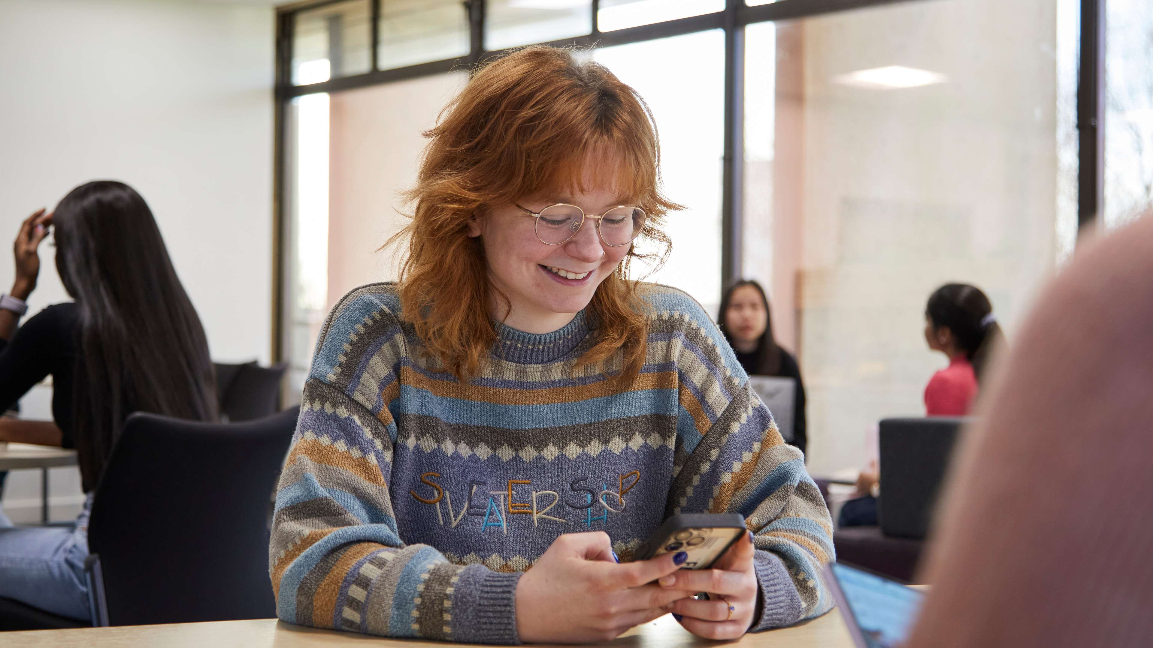 Student in the Library looking at a phone