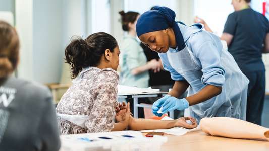 Children and Young People Nursing students taking part in a learning session focused on wound care. The session includes a brief demonstration of ANTT (Aseptic Non Touch Technique) and wound care, followed by students practising the technique on both manikins and each other.