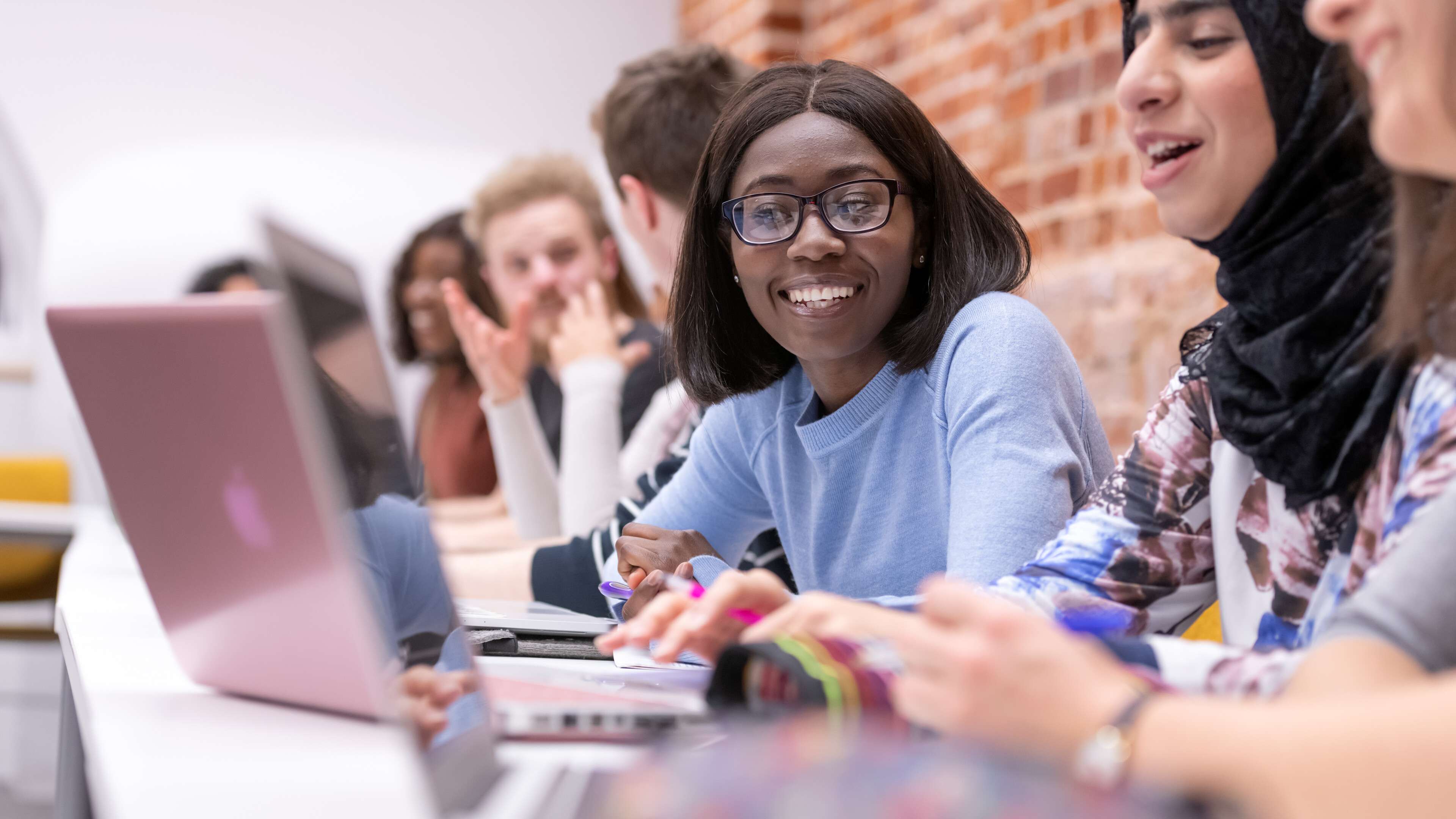 Students smiling looking at their laptops.
