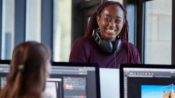 Student with headphones in front of some computers