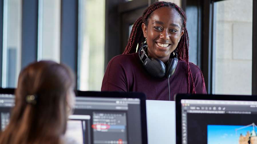Student with headphones in front of some computers