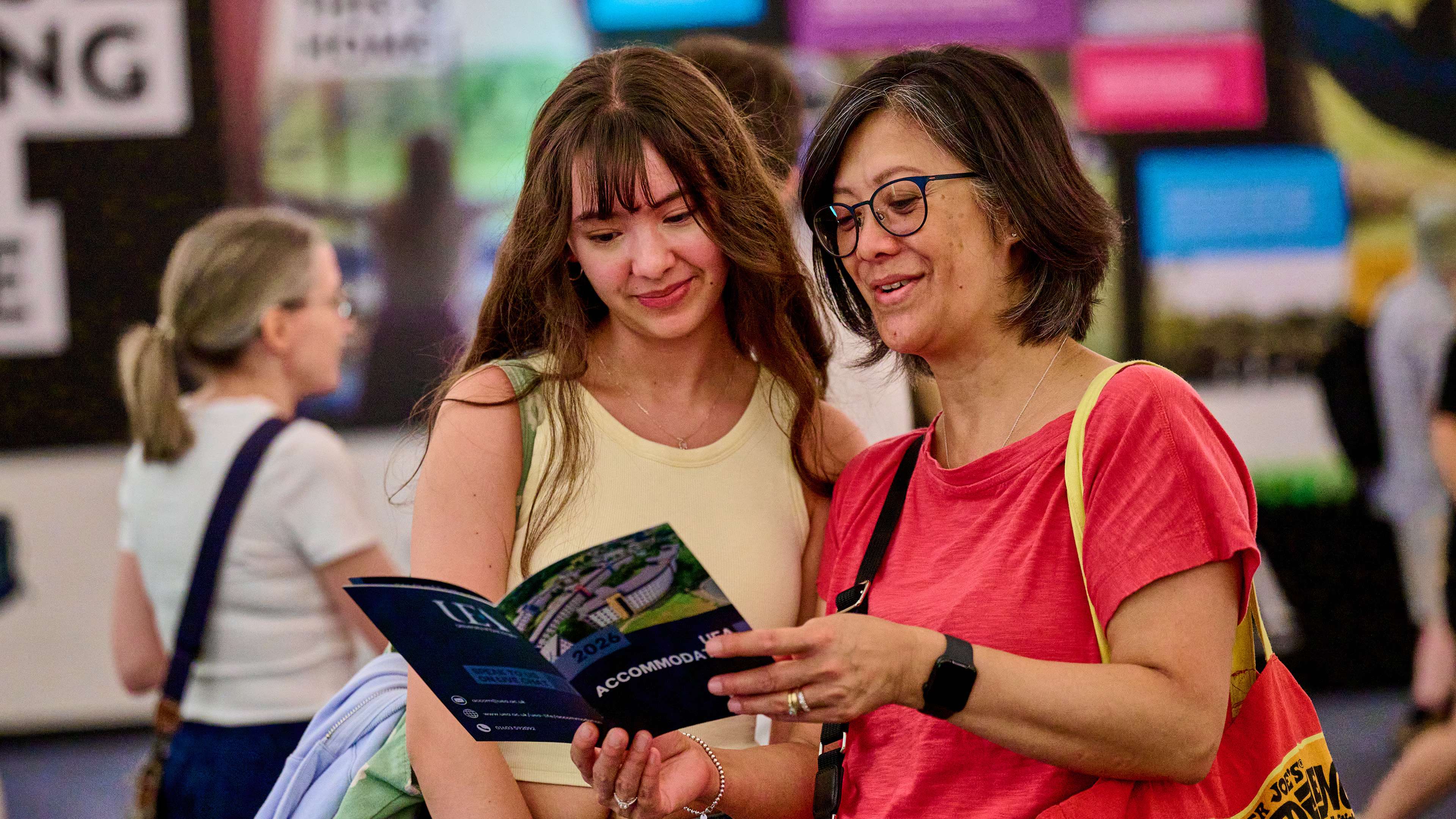 Two people look at an accommodation leaflet at an Open Day.