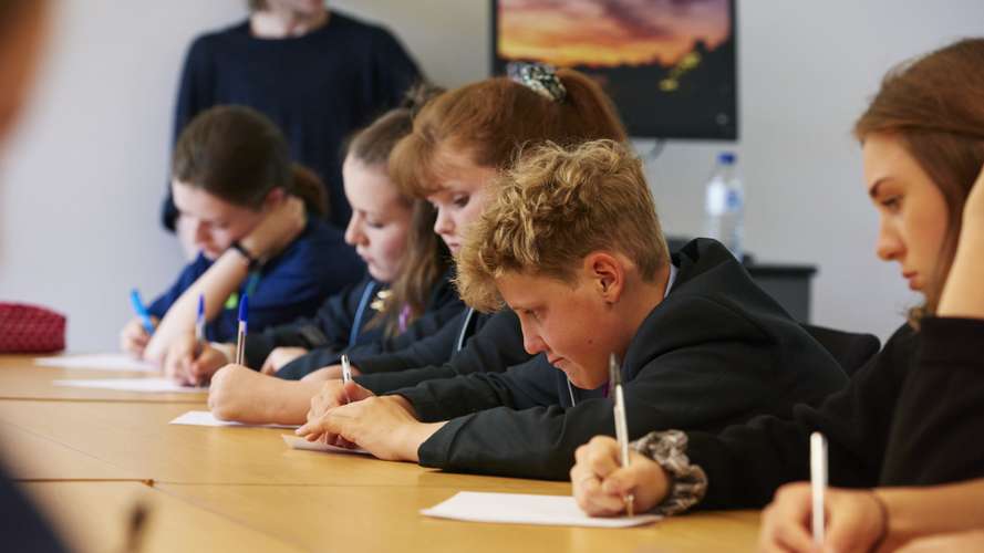School students writing on paper