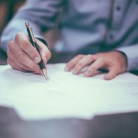 Hand holding a pen and writing on a document