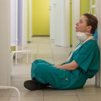 Healthcare worker sitting on the floor looking despondent