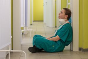 Healthcare worker sitting on the floor looking despondent