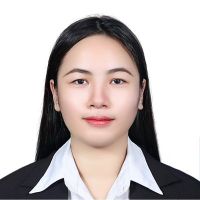 Headshot of a young woman with long dark hair, wearing a black blazer and white collared shirt against a plain white background.