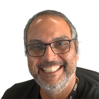 Smiling person with glasses and a beard, wearing a black shirt and lanyard.