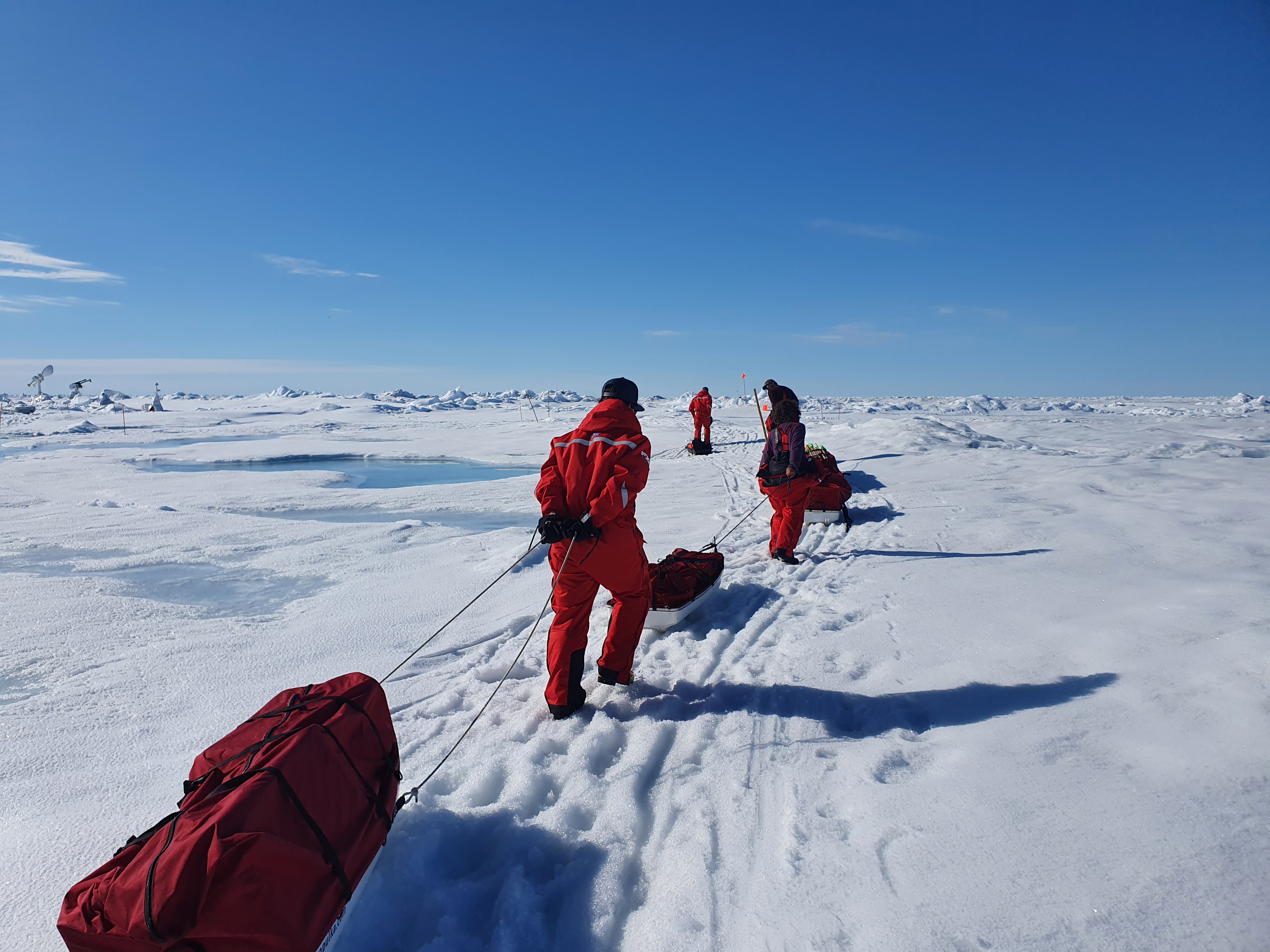 Team ECO walking through snow, pulling their belongings on sledges
