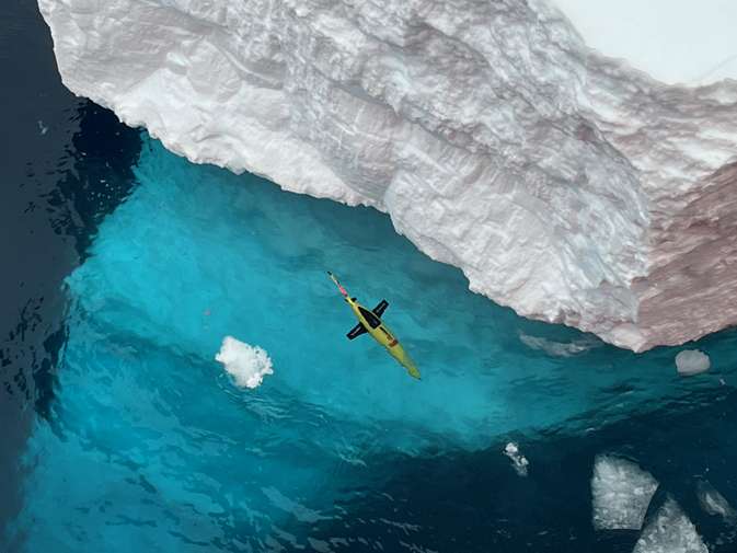 A glider can be seen floating in very clear seawater. It is next to an iceberg.