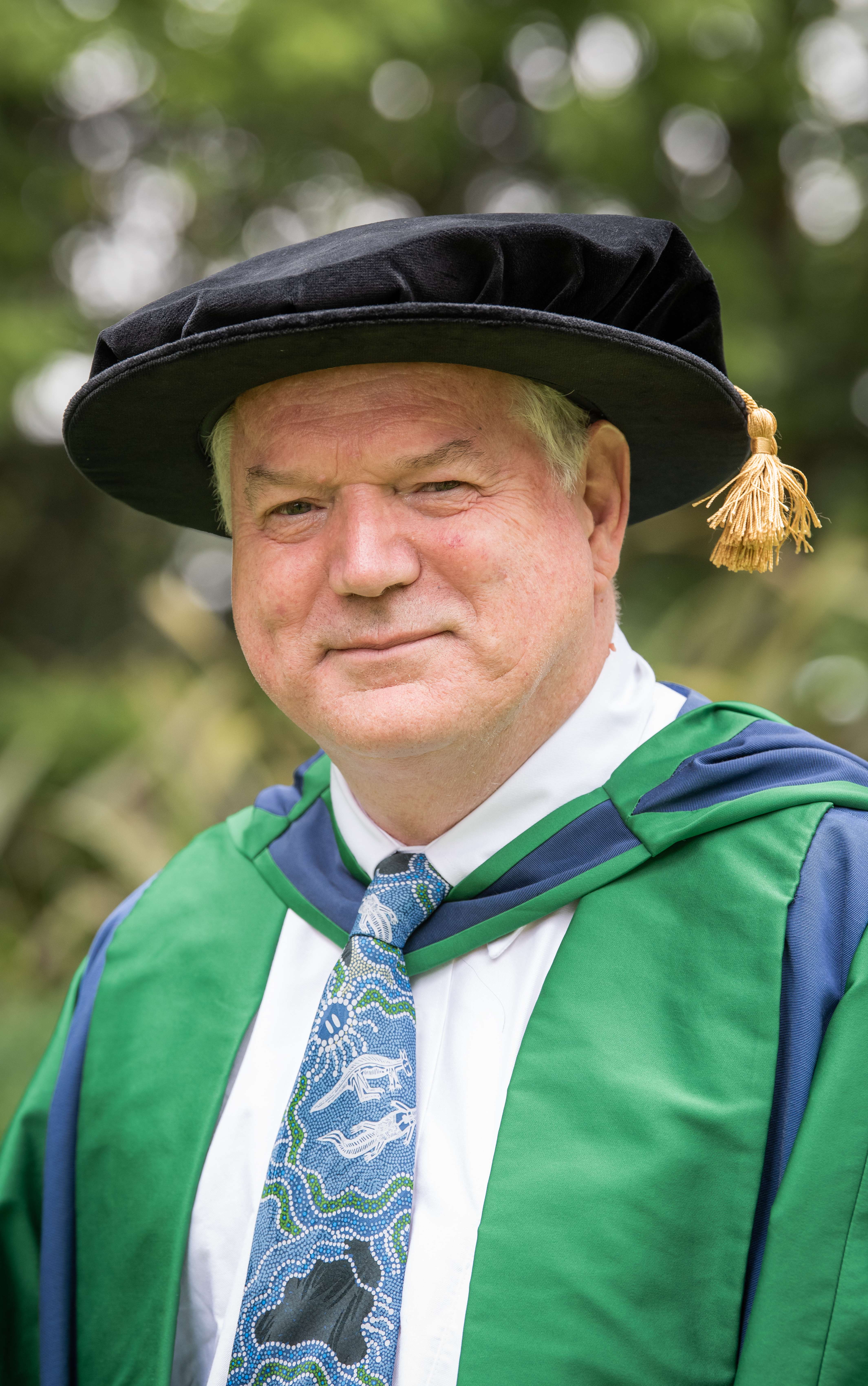 Sir Michael Houghton smiling into the camera in his graduation robes