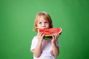 Small child eating huge watermelon slice 