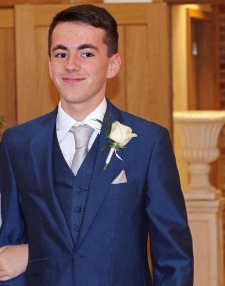 Guy in navy suit with white corsage smiling