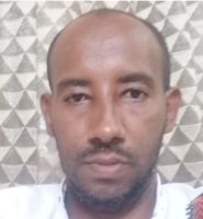 A person with a neutral expression, wearing a white shirt, is in front of a patterned background with geometric shapes.