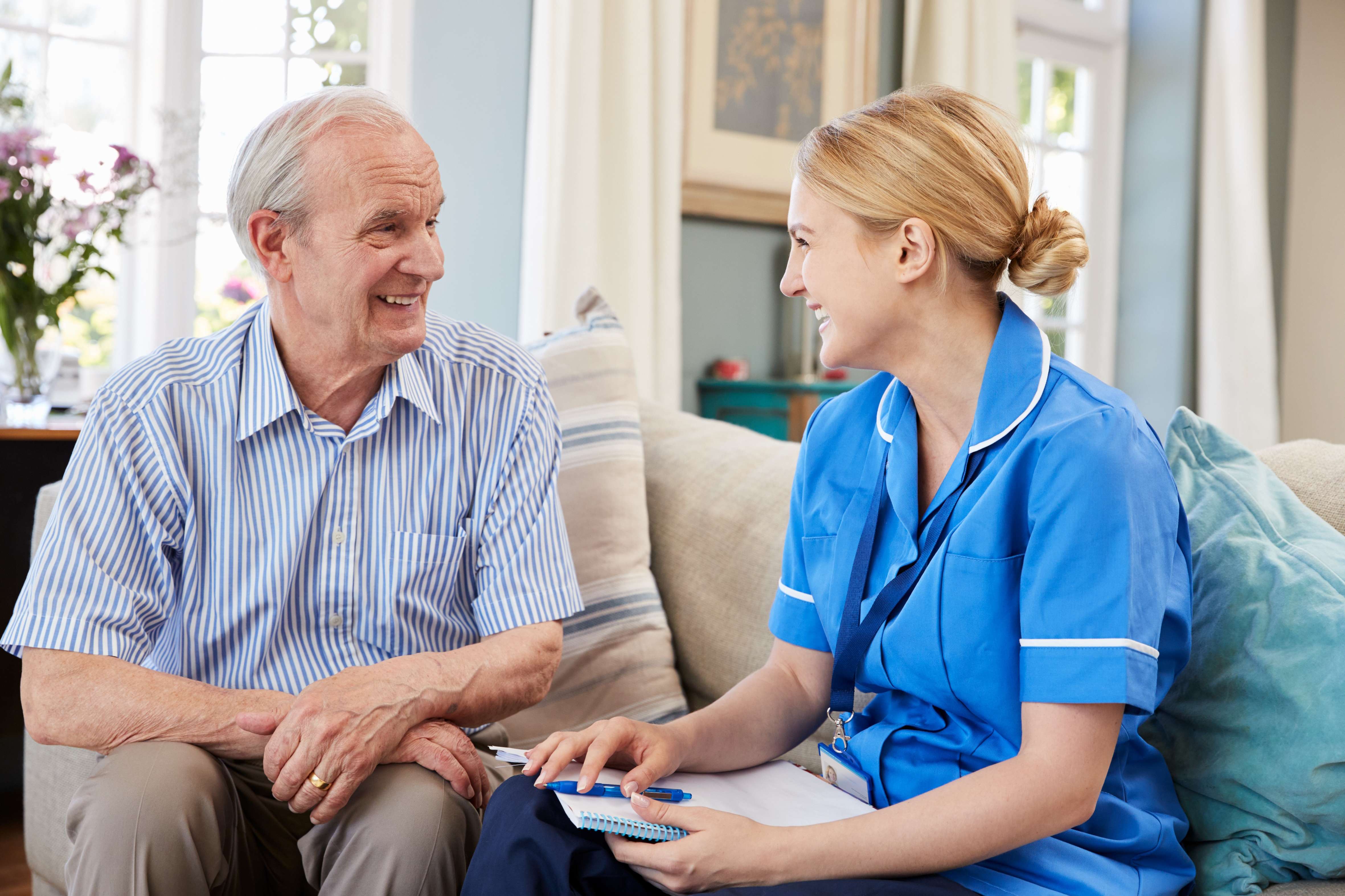 A nurse with an elderly man making notes