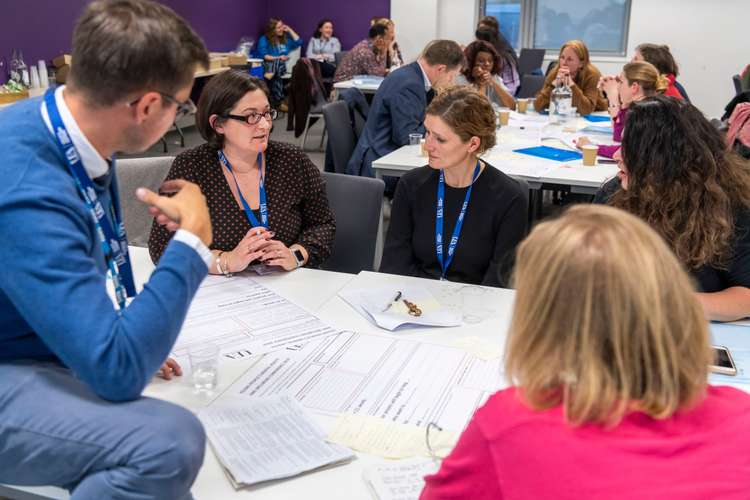 People at a UEAHSCP event, discussing at a table