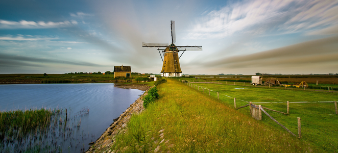 a summery windmill next to a river