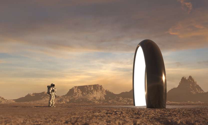 An astronaut on another planet stares at a portal.
